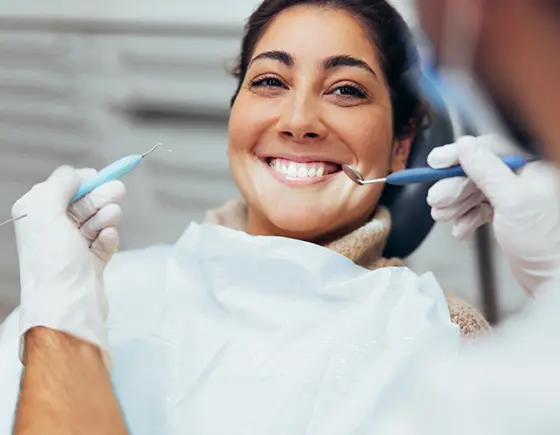 A woman smiling in a dentist chair before a procedure.