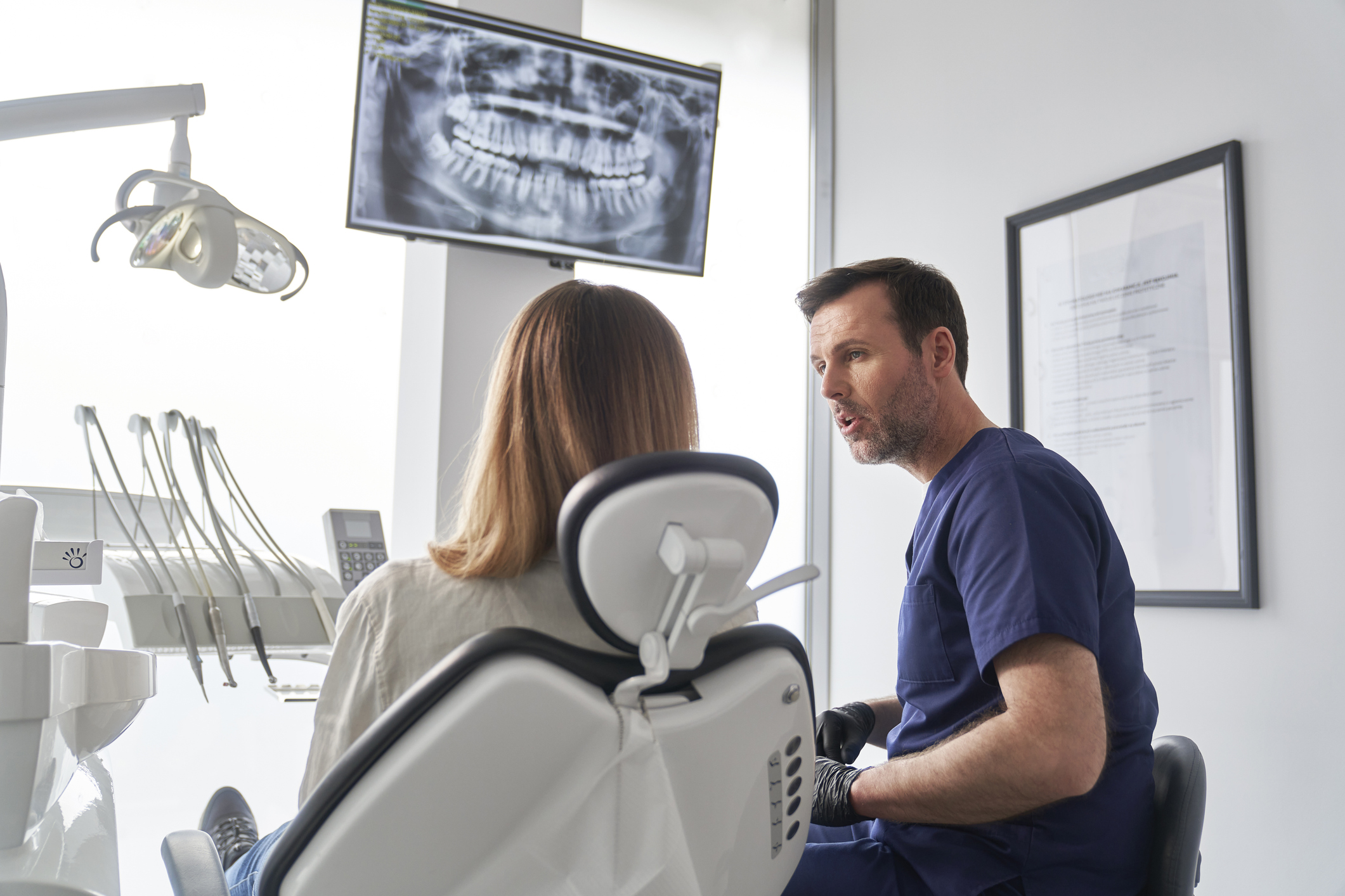 A periodontist reviewing a dental x-ray with a patient